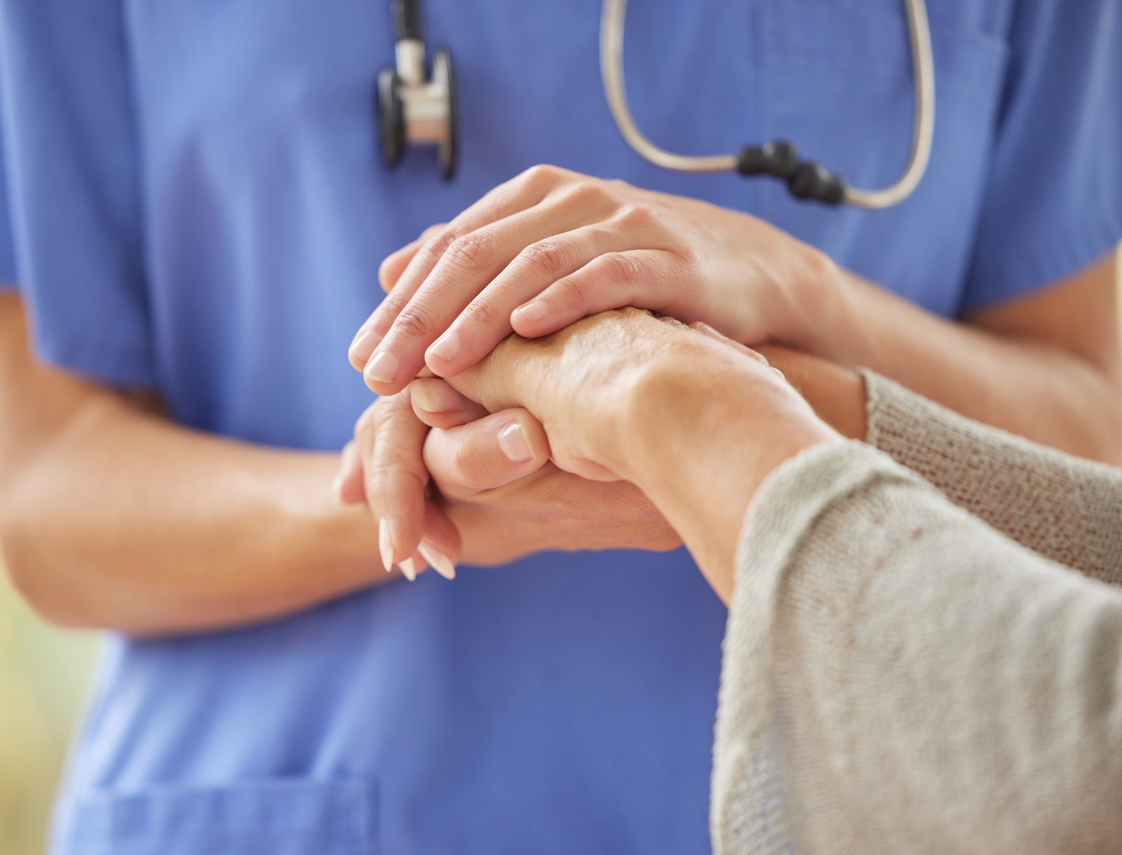 A nurse gently holding the hands of a patient
